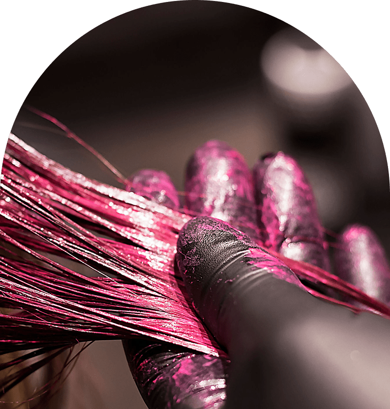 Gloved hand applying pink hair dye.